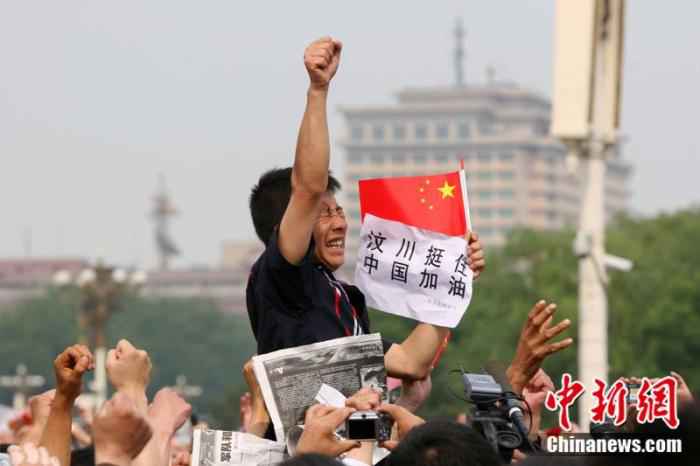 2008年5月19日,北京天安门广场上的民众为地震遇难者默哀,一位来自四川的男子高举右手为家乡加油。中新社记者 富田 摄 汶川地震十二年:遥忆悲伤,记住灾难中不屈的精神